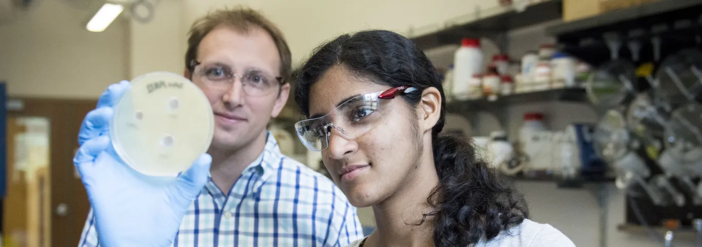 students and professor looking at petri dish